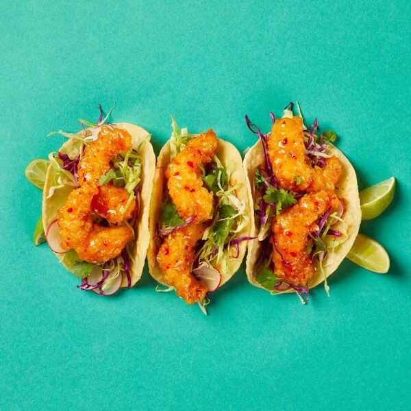 Three Crispy Shrimp Tacos with limes on the side