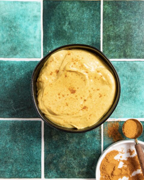 Curry Aioli in a black bowl on a countertop with spices