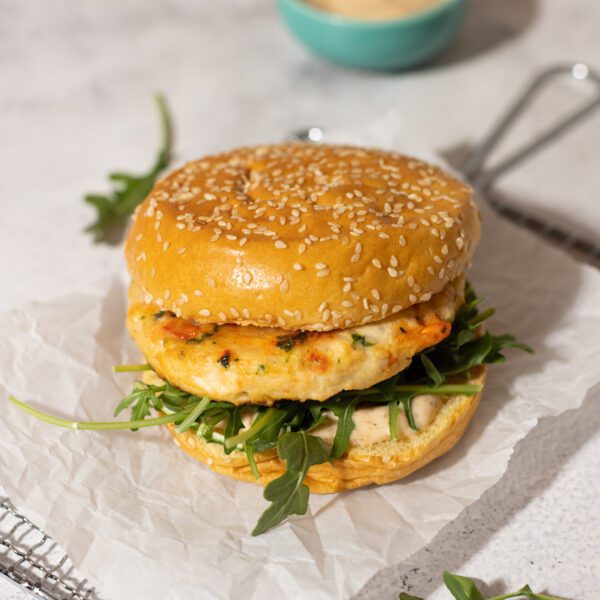 Assembled burger with Social Kitchens Premium Shrimp Burger, arugula, and spicy Cajun aioli sauce.