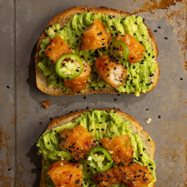 Overhead view of two sweet & spicy shrimp avocado toasts on a metal sheet pan.