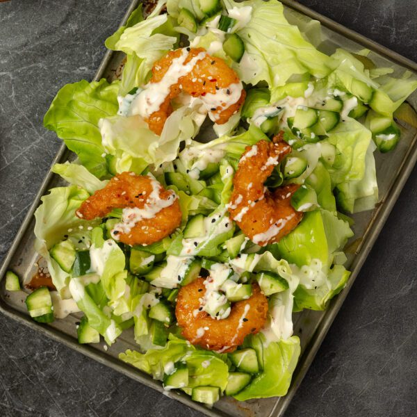 Overhead view of Bang Bang Shrimp Salad on a metal baking tray over a charcoal stone tabletop.