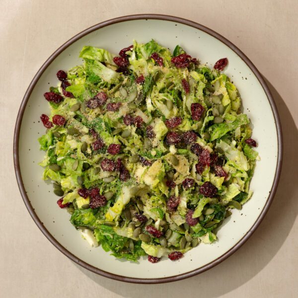 Overhead view of a fall caesar salad on a ceramic plate, served on a neutral stone tabletop.