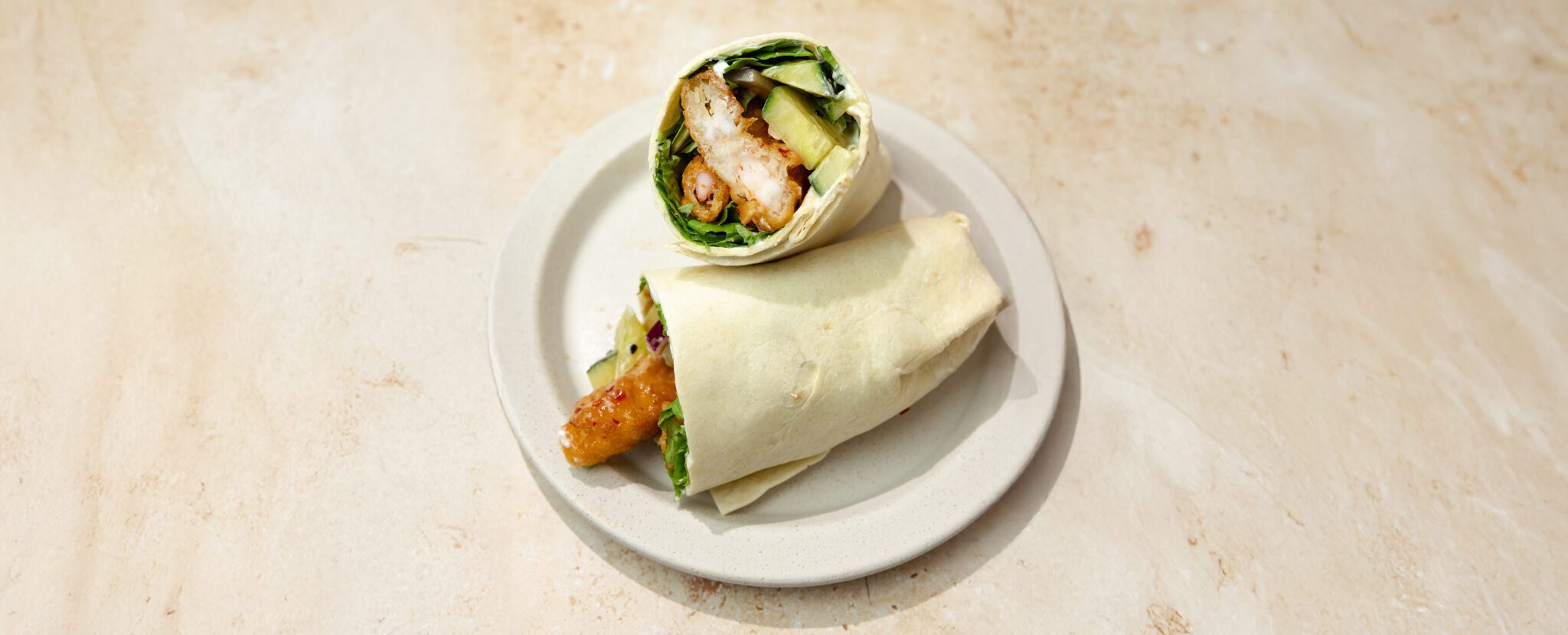 Three-quarter view of Sweet & Spicy Shrimp Wraps cut in half with one propped up against another.