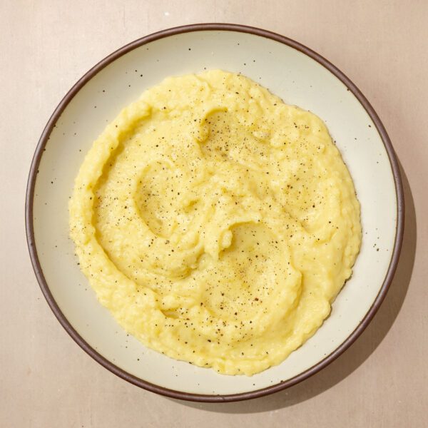 Overhead view of Miso Butter Mashed Potatoes on a white ceramic plate over a warm beige tabletop.