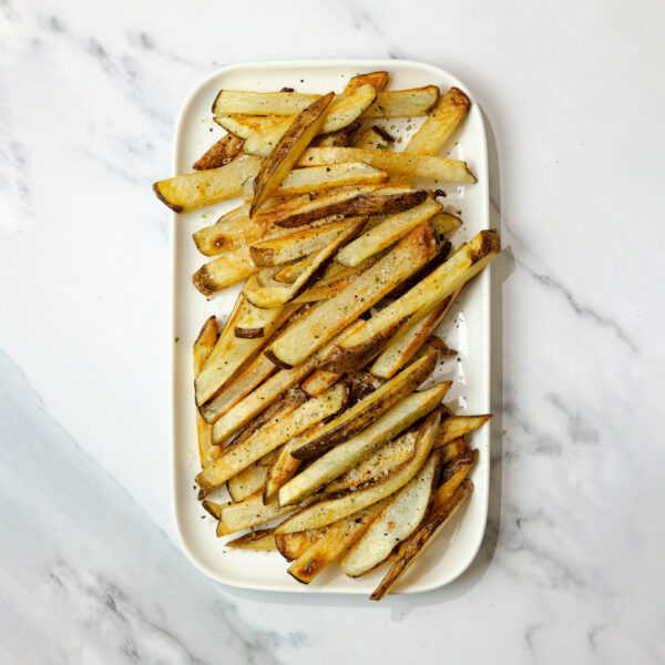Overhead view of oven baked fries on a large white rectangular plate over a marble tabletop.