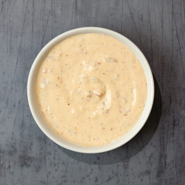 Overhead view of Spicy Chipotle Aioli in a white ramekin served over a gray wood tabletop.