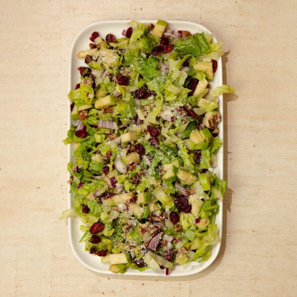 Overhead view of a large rectangular platter of Autumn Chopped Salad, served over a natural linen tablecloth.